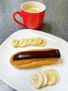 Kırmızı bardakta aromatik kahve, beyaz tabakta çikolata ve dilimlenmiş muz, tatlı, sabah