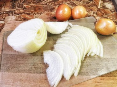 Bıçak ve kesme tahtasıyla dilimlenmiş soğanlar.