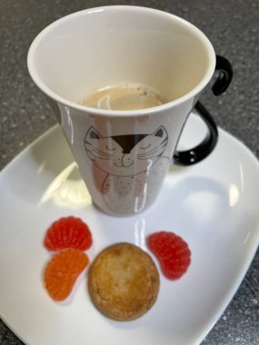 Kahve masasında bir kediyle, beyaz bir tabakta marmelat, şeker, kurabiye, şeker, günaydın, kahvaltı