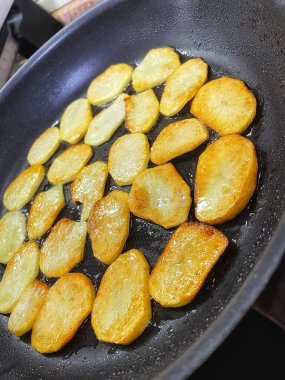 Çıtır çıtır patatesler, dilimler halinde dilimlenir, yağda kızartılır.