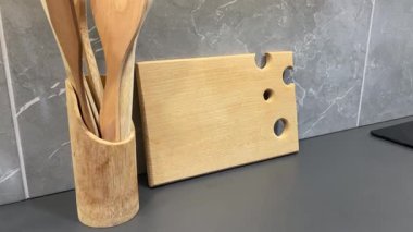 Mutfak masasında tahta kaşıklar ve spatulalar var. Peynir dilimlemek için bir tahta.