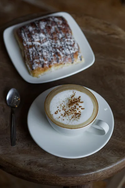 Cappuccino de aroma com croissant de chocolate na mesa de madeira vintage redonda — Fotografia de Stock