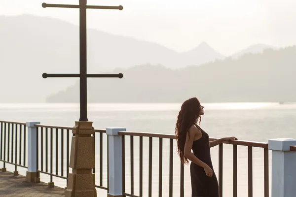 Woman in black dress watching sunrise at the empty bridge. Morning mood