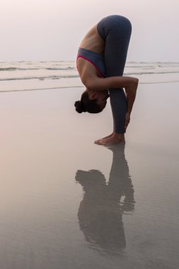 Genç kadın gün batımında sahilde yogadan poz pratik ince