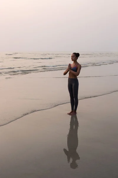 Giovane donna magra che pratica posa da yoga sulla spiaggia al tramonto — Foto Stock