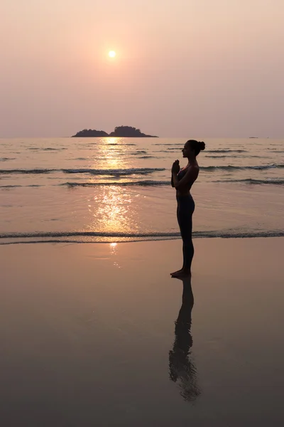 Giovane donna magra che pratica posa da yoga sulla spiaggia al tramonto — Foto Stock