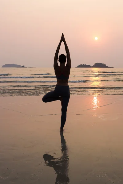 Giovane donna magra che pratica posa da yoga sulla spiaggia al tramonto — Foto Stock