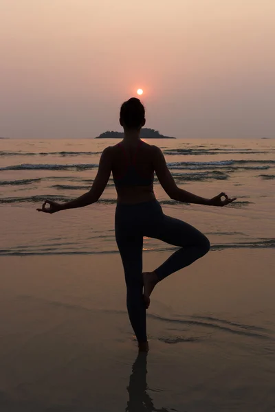 Giovane donna magra che pratica posa da yoga sulla spiaggia al tramonto — Foto Stock