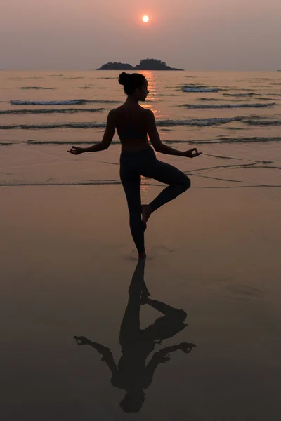 Giovane donna magra che pratica posa da yoga sulla spiaggia al tramonto — Foto Stock