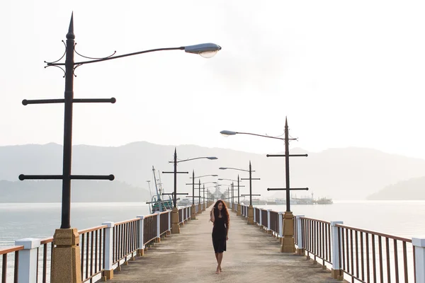 Donna con lunghi capelli neri che cammina sul ponte vuoto al mattino — Foto Stock