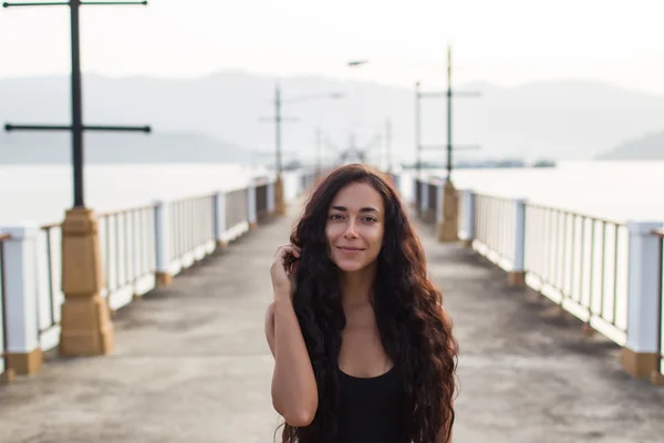 Женщина с длинными черными волосами ходит по пустому мосту утром — стоковое фото