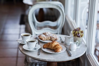 Frehcn kahvaltı taze kruvasanlar ve beyaz masada sıcak kahve ile