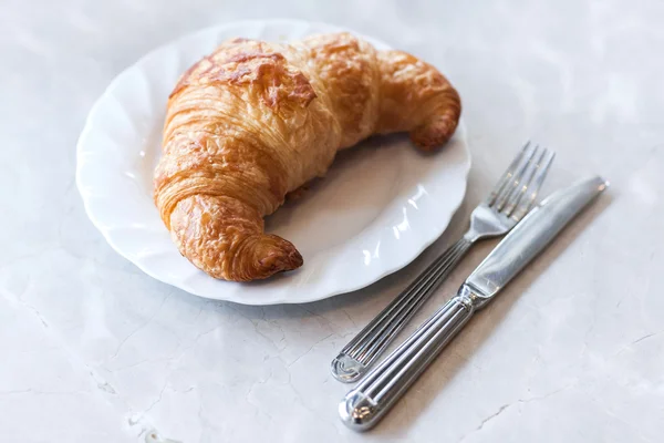 Frisches Buttercroissant auf weißem Tisch — Stockfoto