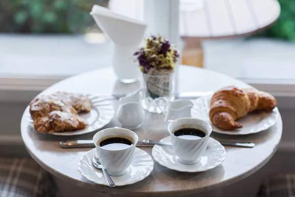 Frehcn snídaně s čerstvými croissanty a horká káva na bílém stole — Stock fotografie