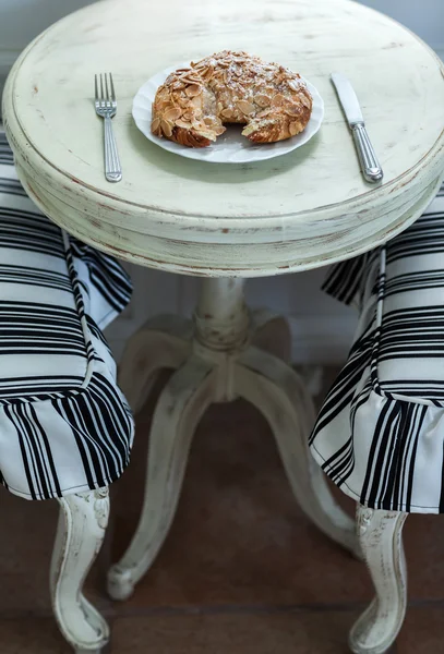 Croissant de amêndoa delicioso na mesa branca vintage — Fotografia de Stock