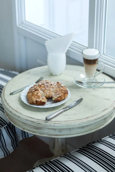 Lahodné mandlový rohlík na vinobraní bílý stůl s horkou kávu latte — Stock fotografie