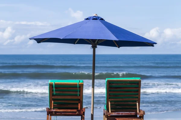 Blue umbrella with two recliners at the ocean coast — Stock Photo, Image