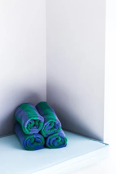 Раскатанные разноцветные полотенца у белой стены — стоковое фото