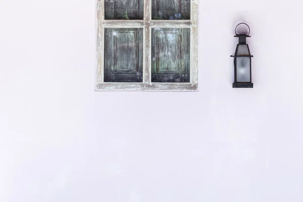 Old metal lamp on white wall near wooden window — Stock Photo, Image