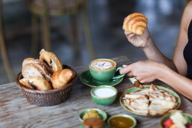 Kahvaltı keyfi ve kruvasan elinde tutan genç kadın. Sabah keyfi