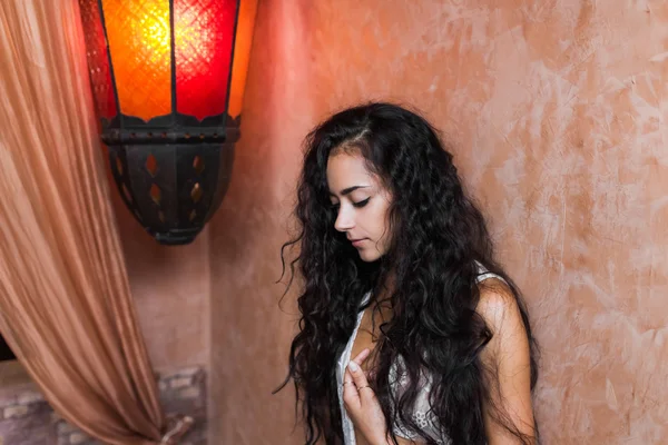 Belle femme avec de longs cheveux noirs en dentelle blanche lingerie dans la chambre avec lampe vintage — Photo