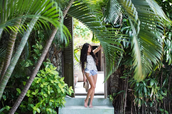 Giovane ragazza magra con cappello di paglia in piedi sotto una palma in hotel di lusso — Foto Stock