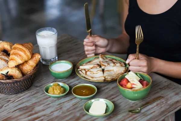 Young woman having breakfast and cut pancakes with golden fork and knife — Stock Photo, Image