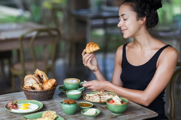 Giovane donna godendo la colazione e tenendo croissant in mano. Buongiorno buon umore — Foto Stock