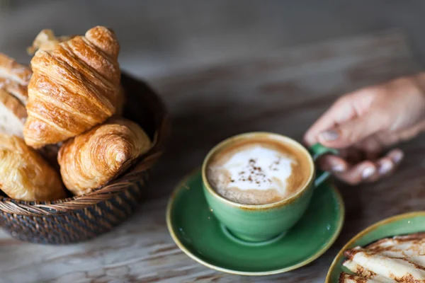 Mujer mano sosteniendo taza de cappuccino aroma en el desayuno con panqueques — Foto de Stock