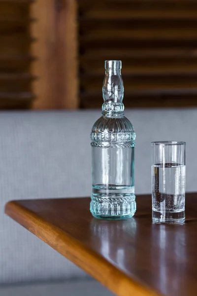 Garrafa de vidro com água potável fresca na mesa de madeira — Fotografia de Stock