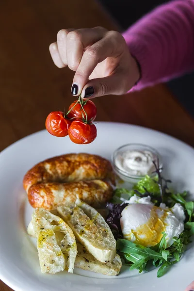 Colazione con salsicce fritte, pomodorini al forno, uova in camicia e verdure — Foto Stock