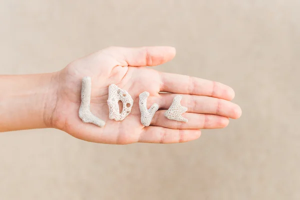 Palabra de amor hecha de conchas en la mano —  Fotos de Stock