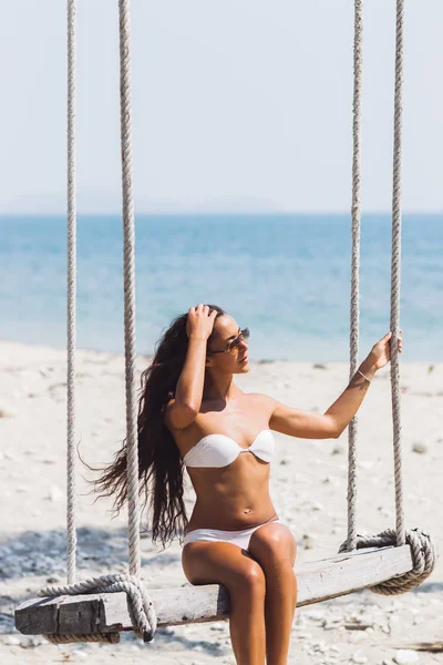 Ragazza si siede su un'altalena sulla spiaggia — Foto Stock