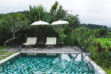 Havuzu iki şezlong şezlong ve şemsiyeler