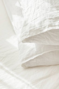 Beyaz, tekstil kumaşından yastıklara yakın çekim. Güzel yatak, sabah ışığı.