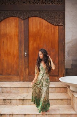 Ahşap kapının arkasında yeşil ipek elbiseli esmer kıvırcık kadın portresi. Asya tarzı ve mimarisi.