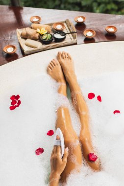 Bacaklarını köpükle yıkayan bir kadın ve doğal lif süngeri kullanıyor. Spa, vücut bakımı, romantik ruh hali..