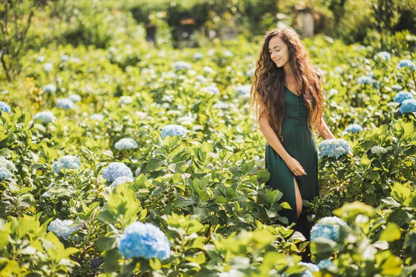 庭で青いアジサイの花を楽しむ緑のドレスの若い美しい女性 園芸と花屋のコンセプト 花のプランテーション 自然の美しさ — ストック写真