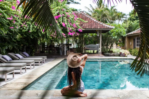 Giovane donna magra rilassante vicino alla piscina con cappello di paglia — Foto Stock