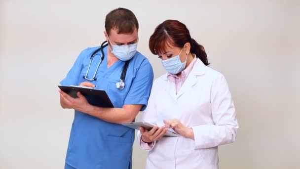 Doctores de un hombre y una mujer discutiendo la historia clínica — Vídeos de Stock