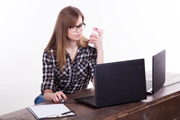 コーヒーを飲みながらノート パソコンに座ってオフィスで女の子 — ストック写真
