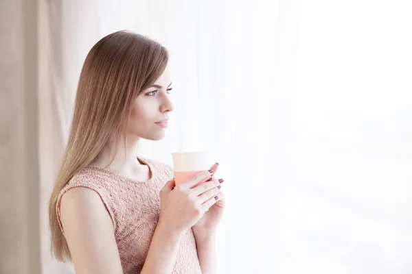 The girl with the Cup looks out the window — Stock Photo, Image