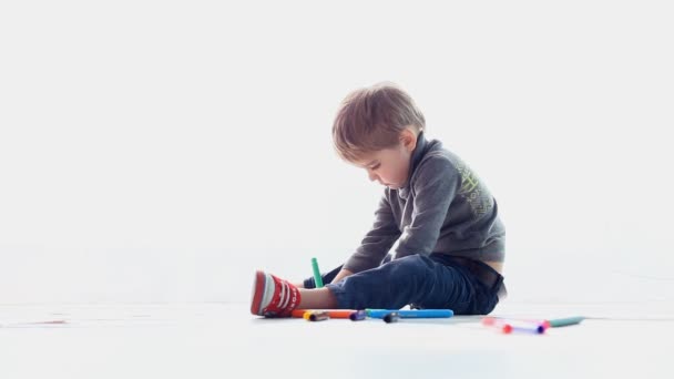 Un niño pequeño se sienta dibuja — Vídeos de Stock