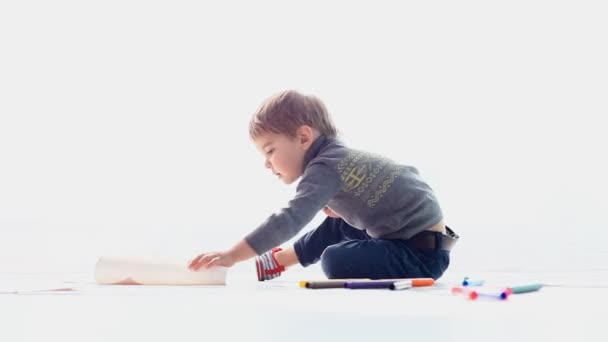 Um menino pequeno senta-se desenha — Vídeo de Stock