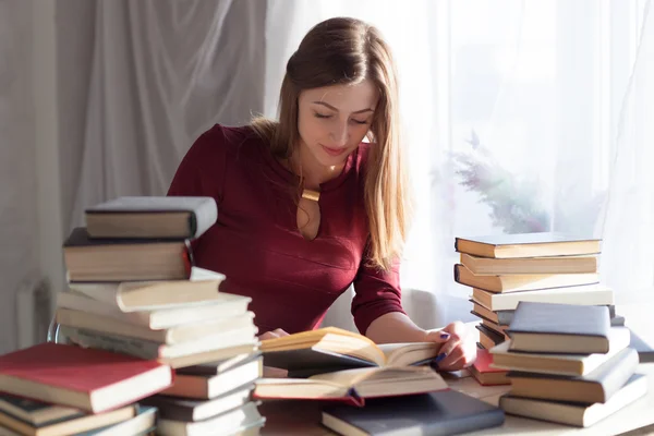 Menina senta-se livros e ler um livro — Fotografia de Stock