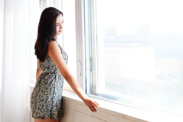 La chica mira por la ventana —  Fotos de Stock