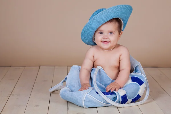 Маленькая девочка в шляпе сидит в пляжной сумке — стоковое фото