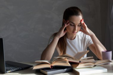 Kız sınava hazırlanıyor ve bir kitap okuyor.