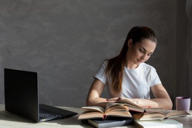 Kız sınava hazırlanıyor ve bir kitap okuyor.