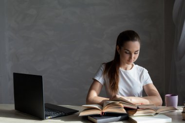 Kız sınava hazırlanıyor ve bir kitap okuyor.